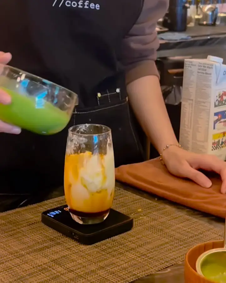 A Waterloo barista pouring a mango matcha and whisking matcha at the bar